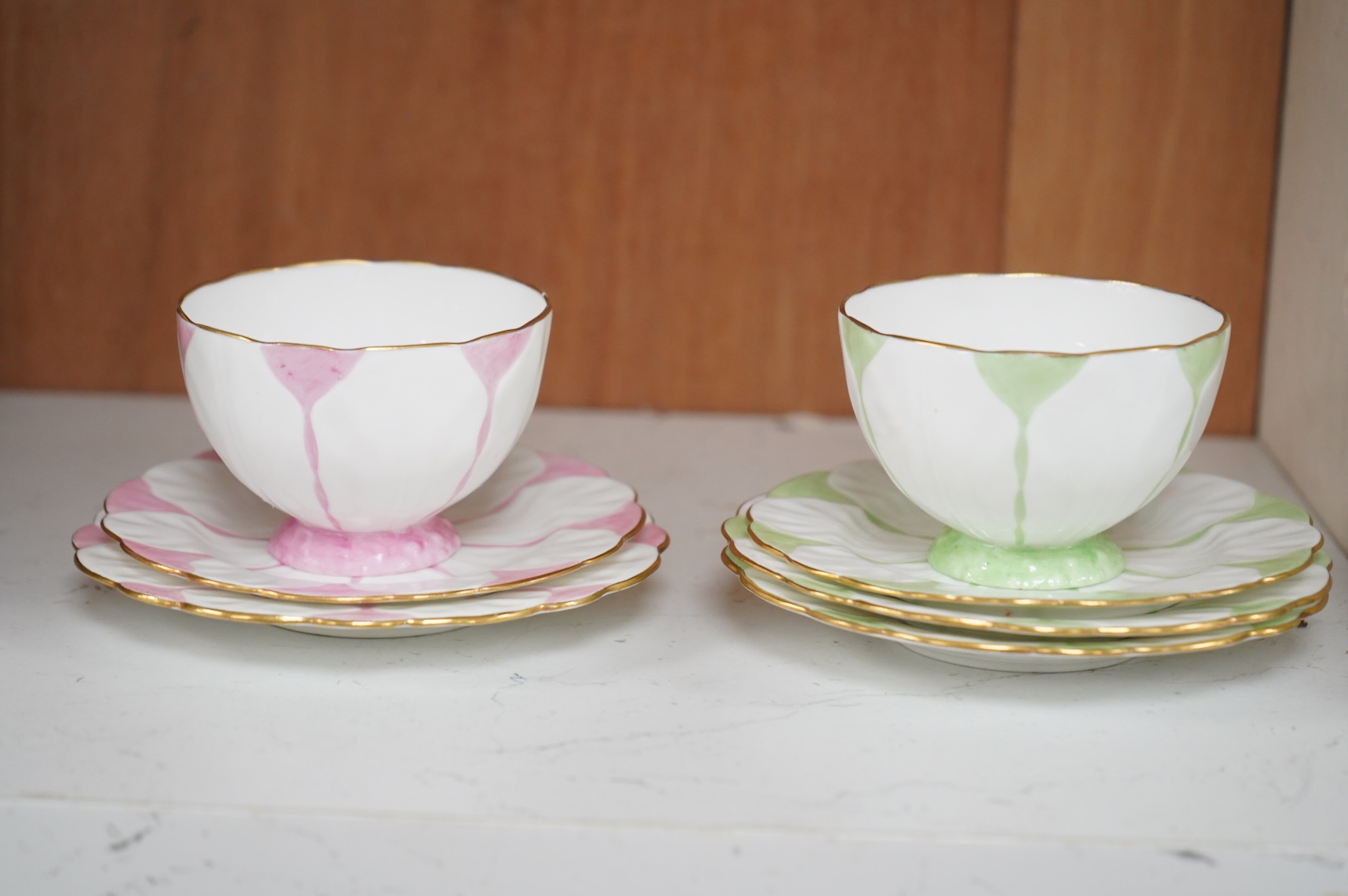 Two Aynsley trios with butterfly handles and one extra saucer, numbered 785788
